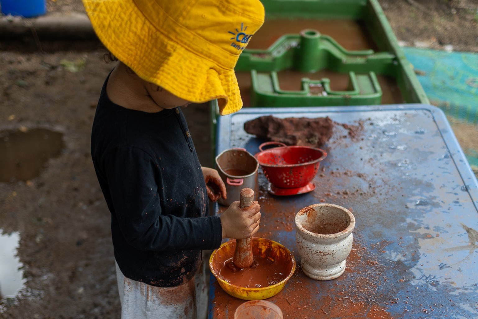 C&K Tully - child mixing mud in the mud kitchen