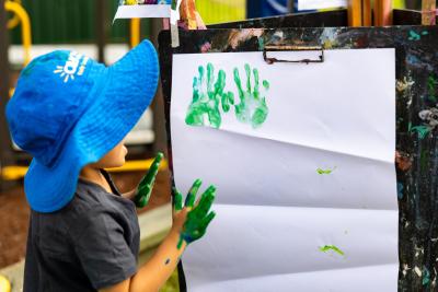 Child placing their painted handprints on an art easel