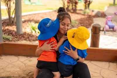Educator cuddling two toddlers