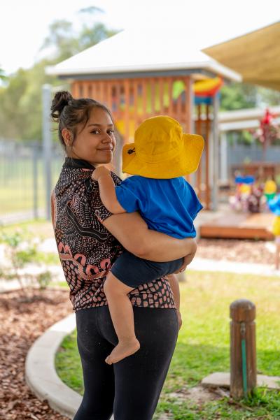 Educator smiling holding a toddler outside