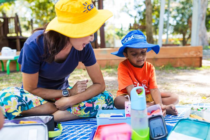 Educator and kindy child eating lunch outside