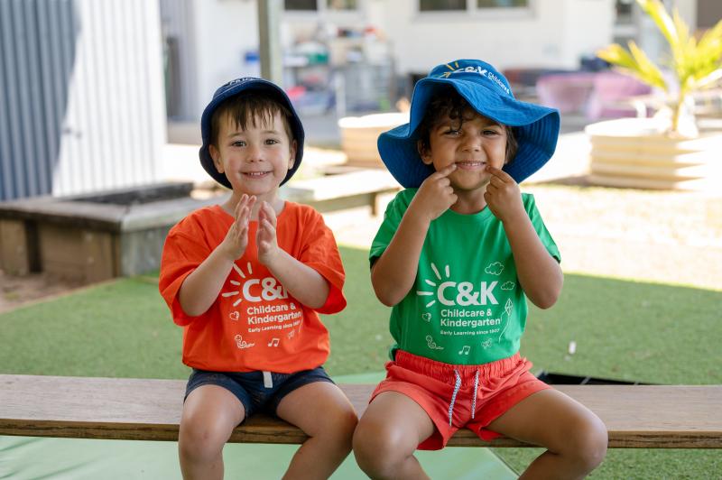 Two smiling kindy children sitting on obstacle course