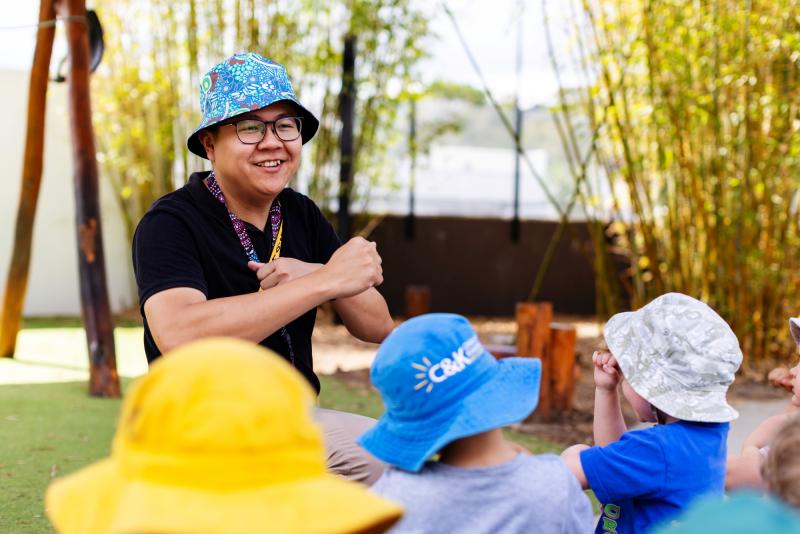 Educator singing and dancing with a group of children outside