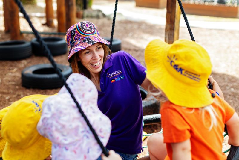 Educator smiling and children while on the swing outside