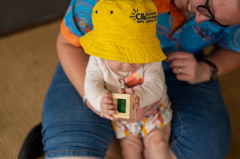 Educator with toddler sitting down and engaging
