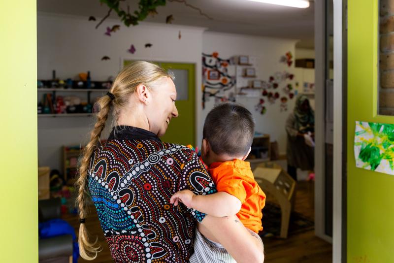 Smiling educator carrying baby inside