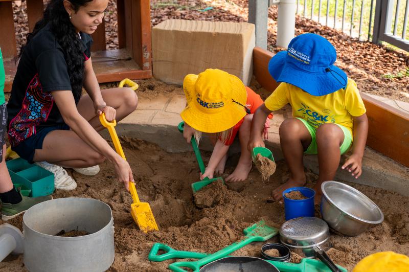 Educator playing with children in the sandpit