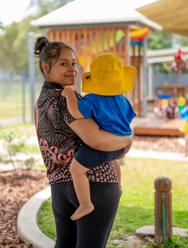 Educator holding a child, smiling at the camera
