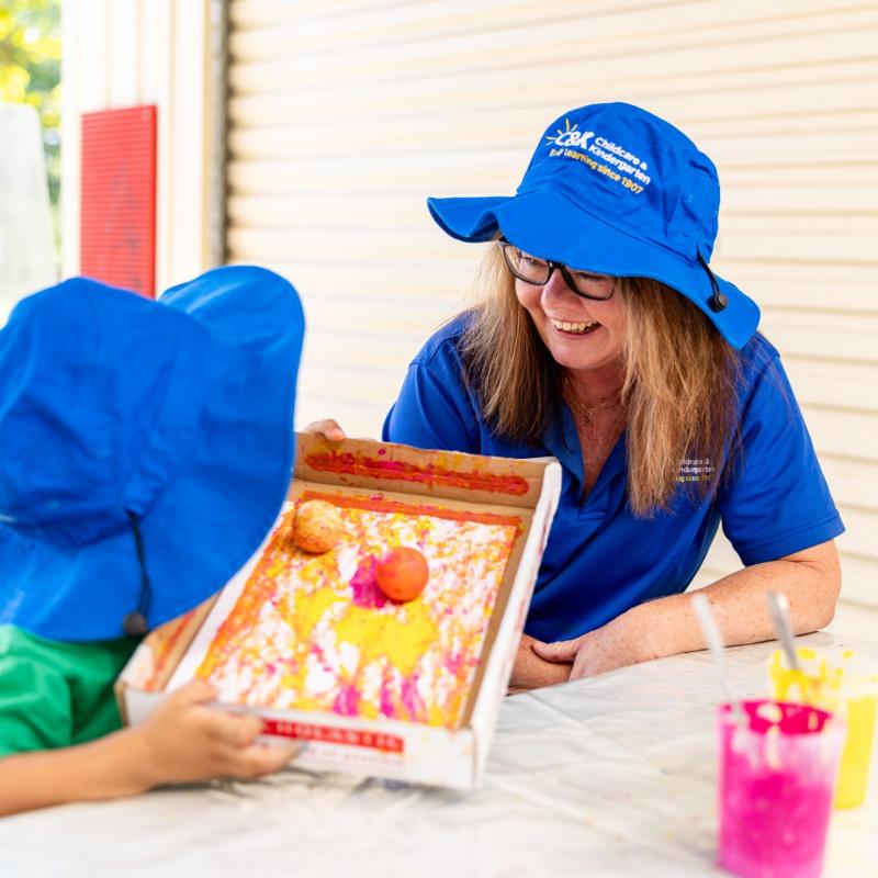 Home page slider 2 - educator smiling at child while they create art