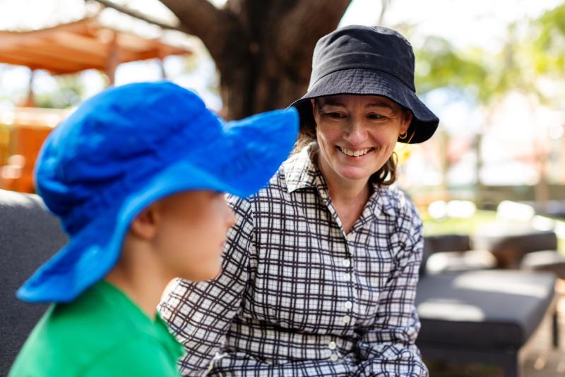 Educator smiling at child sitting outside