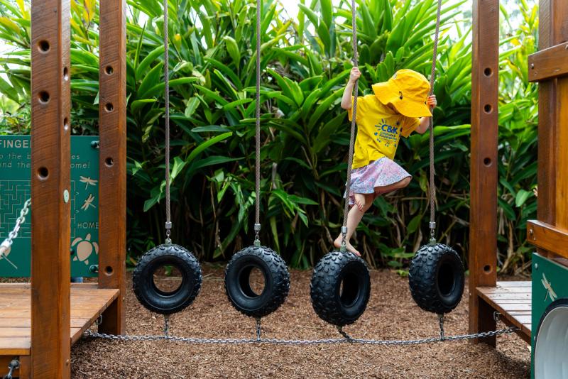 Kindy child climbing over hanging tyres