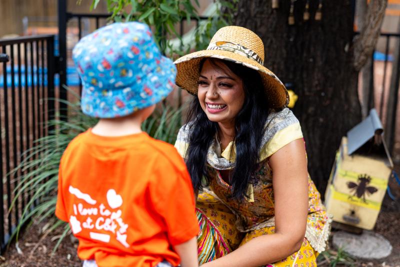 Educator crouching down to be eye-level with a child, smiling