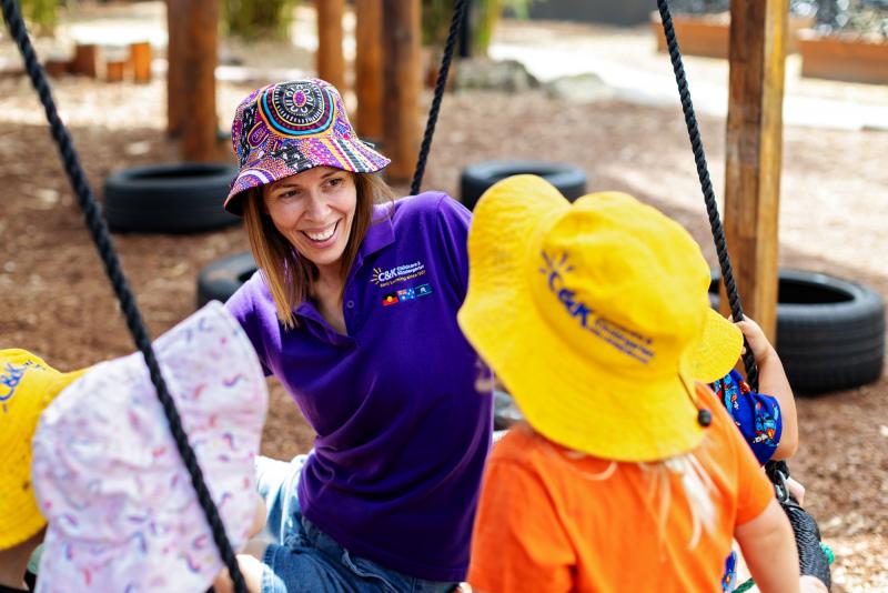 Smiling educator on the swing with children