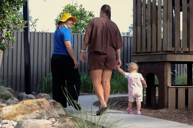 Parent and toddler walking outside with an educator