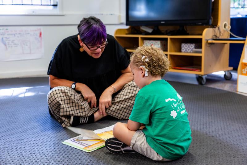 Educator and kindy child reading together