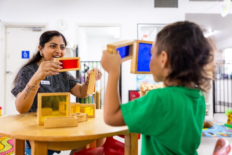 Child and educator holding up colourful blocks to the light