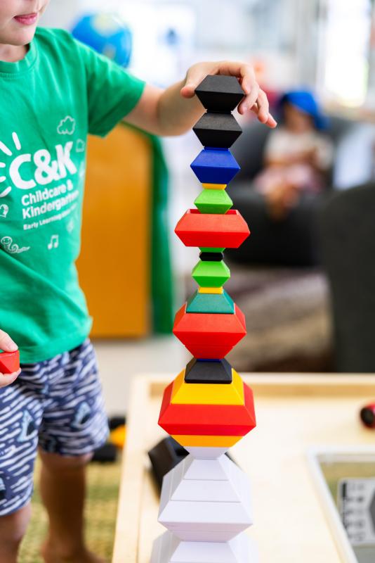 Kindy child stacking colourful pebbles